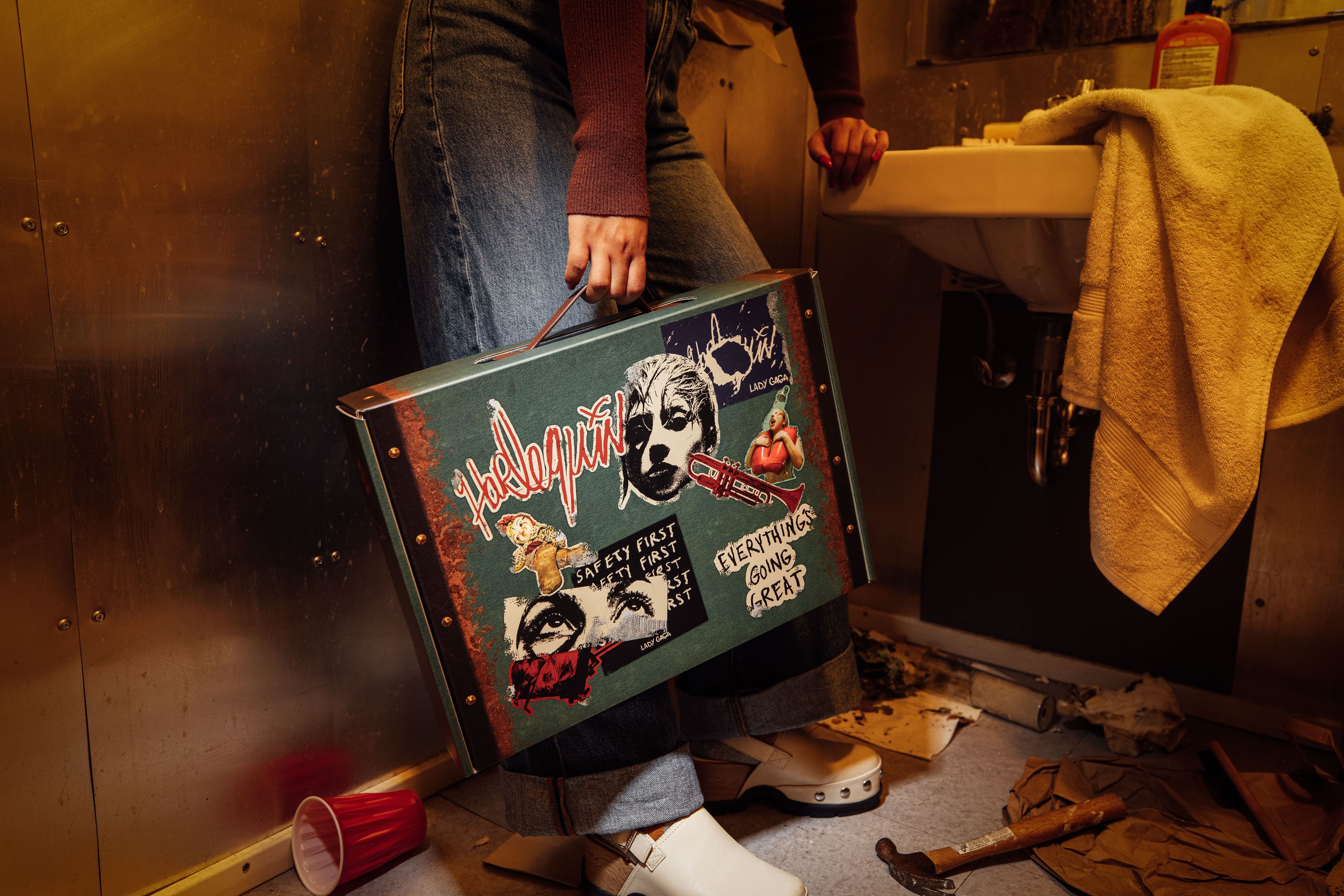 woman in a dirty bathroom holding the Harlequin box